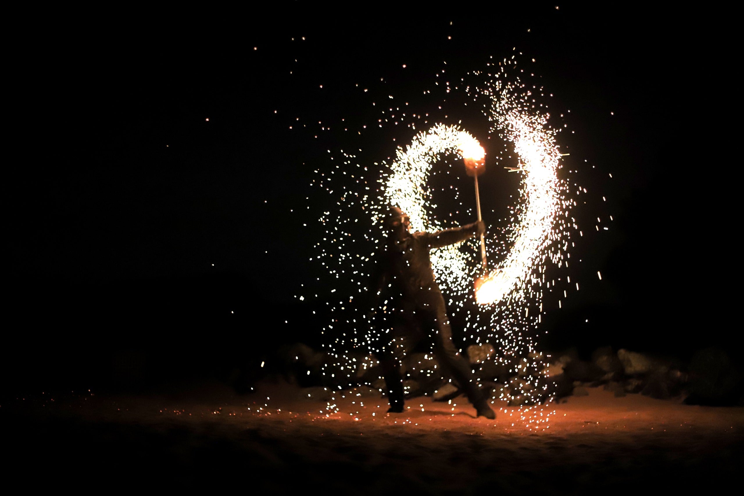 Person performing with fire at night, creating circular patterns of light at desert safari Dubai.
